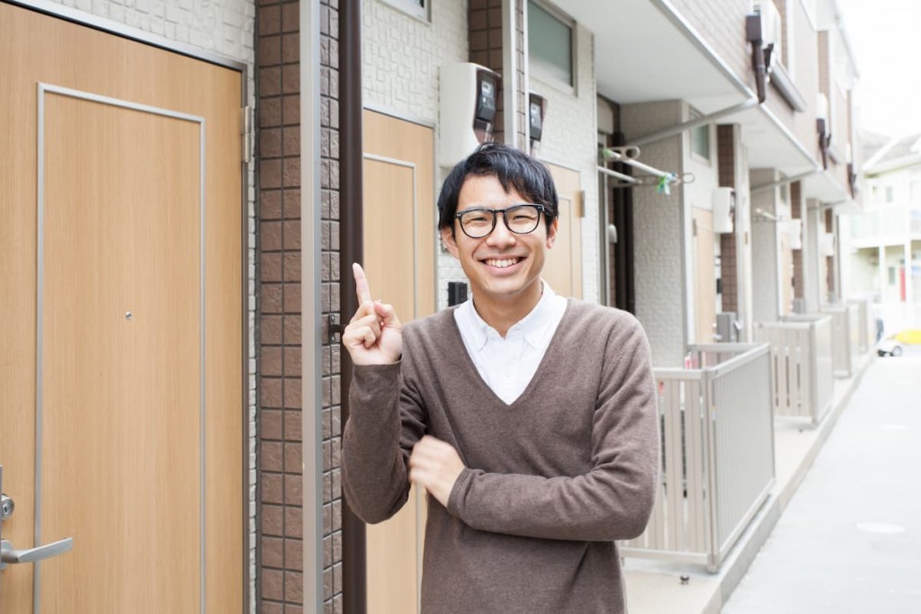 アパートの前で笑顔の男性